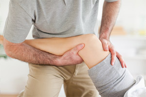 Medical professional holding a leg for knee therapy.